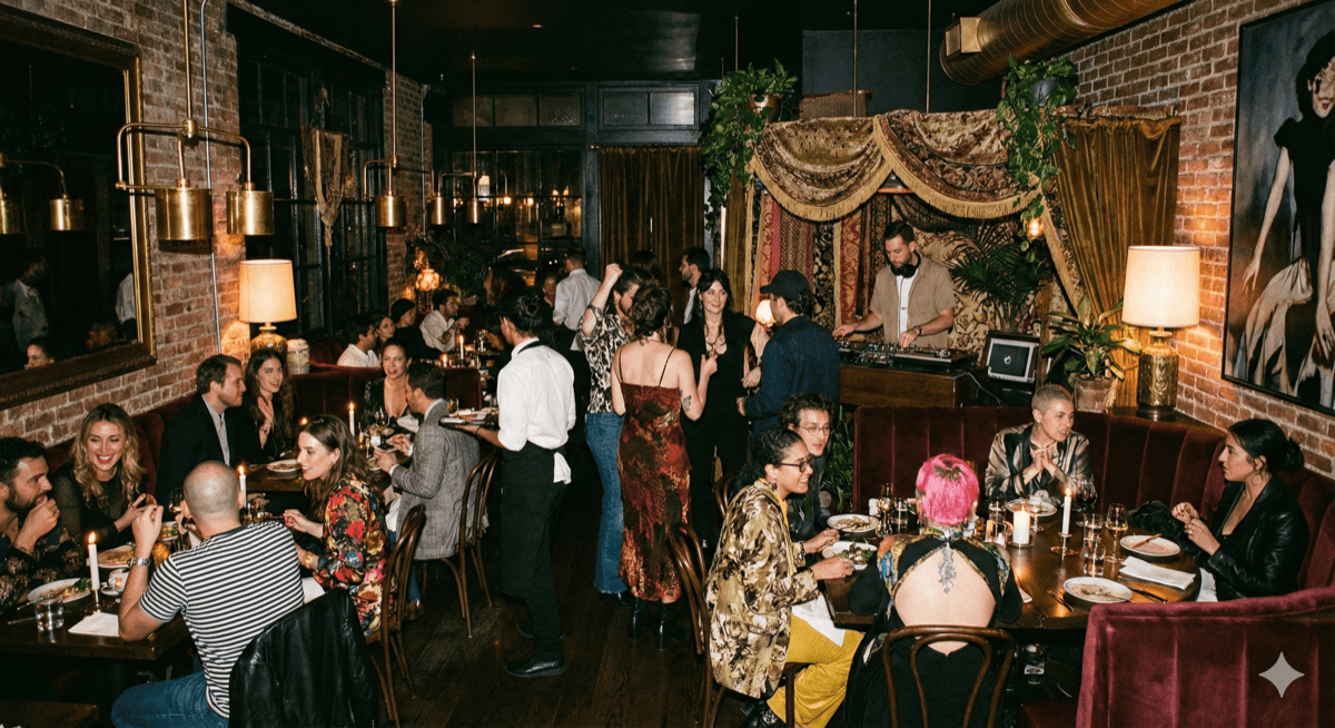 Lively restaurant with DJ and guests dining in warm ambient lighting